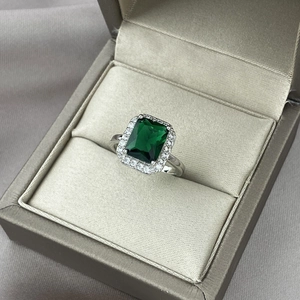Ring met smaragd geslepen groene edelsteen en moissanite halo in een luxe juwelendoos