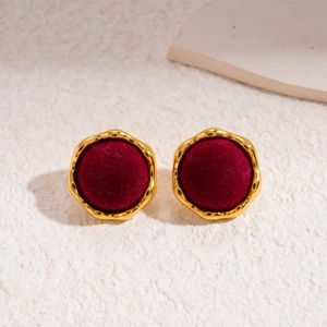 Close-up of vintage gold wavy edged round earrings with deep red flocked texture detail