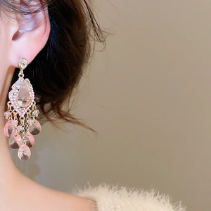 Macro shot of long fringe earrings with pink teardrop stones and pearl tassels