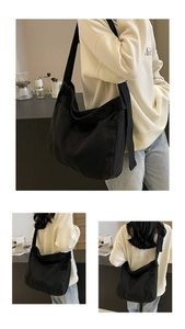 Close-up of a large black cotton canvas messenger bag with wide strap and side pockets