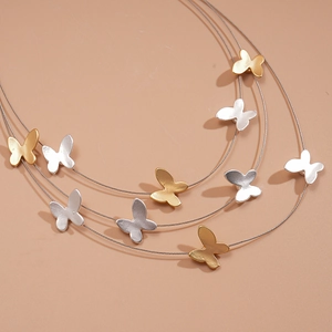 Macro detail of triple-layer metallic necklace with gold and silver butterfly pendants