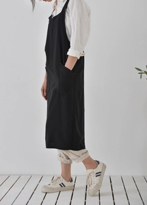 Side view of a long black washed linen apron featuring a large functional side pocket