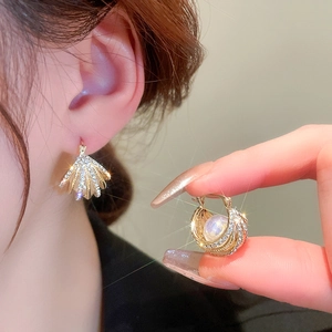 Boucles d'oreilles coquillage plaquées or avec diamants et perles portées par un mannequin