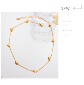 Détail d'un collier doré double couche avec pendentifs cœur et fermoir mousqueton
