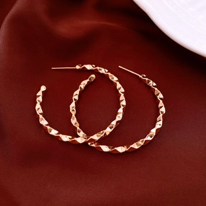 Detail shot of golden geometric diamond-cut earrings on elegant red silk fabric