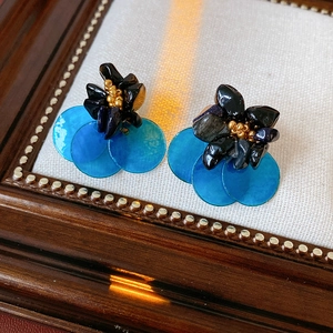 Detailed close-up of vintage style earrings with blue sequins and black floral accents