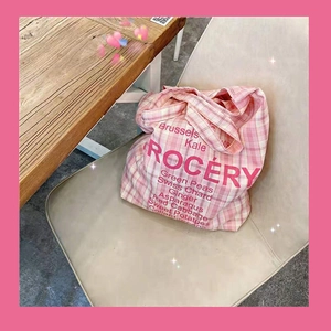 Pink checkered canvas grocery bag with text print on a white chair detail