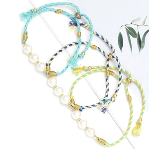 Handmade green rope woven bracelet with glass pearls and gold beads on white background
