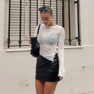 Weißes Oberteil aus Spitze mit Wellenstruktur und schwarzer Lederrock an einem Fashion-Model