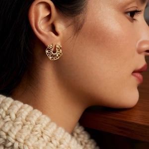 Detailed close-up of a gold hollow geometric stud earring with zircons on a model