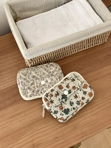 Quilted floral card pouch set with beige leaf patterns and zip closure on wood table