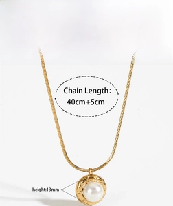 Detail of gold snake chain necklace with pearl pendant featuring diamond pattern metal frame