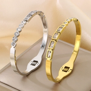 Close-up of gold and silver stainless steel bangles with alternating zircon stones