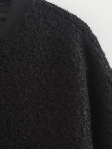 Detailed close-up of black sherpa fleece fabric texture and ribbed knit collar detail