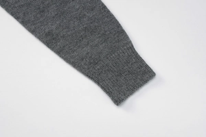 Détail d'un pull en maille gris foncé montrant le poignet côtelé et la texture du tissu