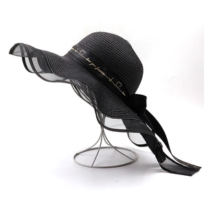 Détail du chapeau de paille noir à large bord avec bord en résille et ruban