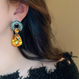 Macro detail of vintage teardrop earrings with amber crystals and teal micro-pave setting