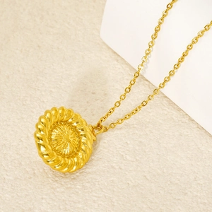 Collier en acier titane doré avec pendentif rond tissé sur fond en lin beige naturel