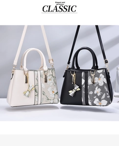 Detail of floral embroidery and bow pendant on stylish contrast color handbags