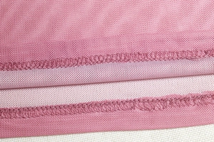 Macro shot of breathable pink mesh fabric with durable double-stitched hem detailing