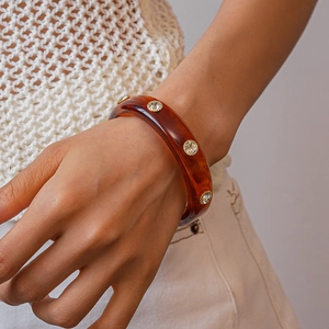 Detailed view of amber resin bangle with crystal rhinestones on a woman's wrist