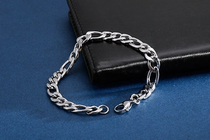 Detailed shot of silver Figaro chain bracelet with lobster clasp on leather wallet