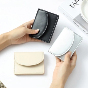 Close-up of minimalist faux leather wallets in black, silver and beige with flap closure