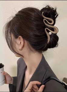 Side view of a large wavy beige hair claw clip with pearl detail on a woman's updo hairstyle