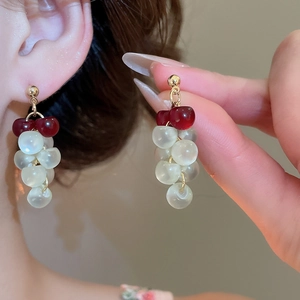 Close-up of red and white resin grape tassel earrings with gold-toned metal details