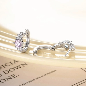 Minimalist silver hoop earrings with pink and blue zircon stones on a beige surface