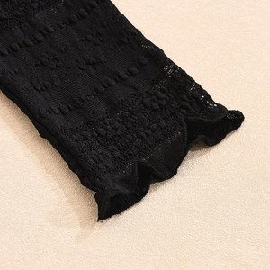 Close-up of the delicate black hollow crochet lace cuffs on a long-sleeved mesh top