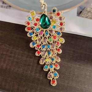 Detailed view of peacock brooch with colorful rhinestones and a large green pear-cut gem