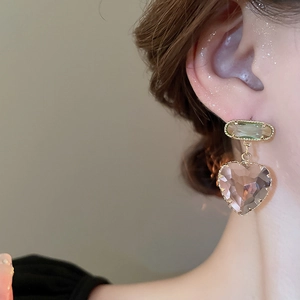 Detailed close-up of crystal heart pendant earrings with green and pink faceted gems
