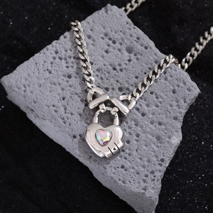 Silver Cuban chain necklace featuring a heart-shaped lock pendant with iridescent gemstone