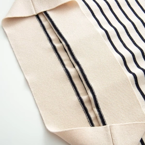 Détail des poignets en maille côtelée à rayures noires sur un cardigan beige