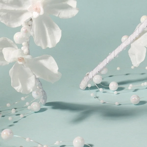 Close-up of white fabric flowers and shimmering beads on a silver ribbon headband