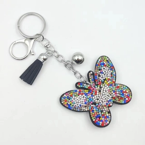 Detail of butterfly keychain with colorful rhinestones, black tassel and silver bell