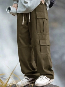 Dettaglio dei pantaloni cargo con tessuto verde oliva, grandi tasche laterali e coulisse