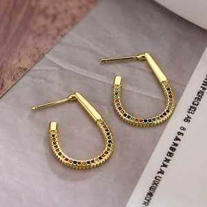 18K gold plated U-shaped earrings with colorful zircon stones on magazine background