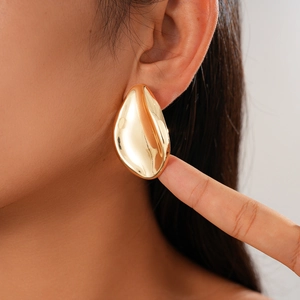 Close-up of a model wearing high-shine gold irregular leaf-shaped teardrop stud earrings