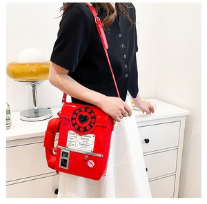 Detail of creative red vintage telephone shaped crossbody bag in glossy patent leather finish