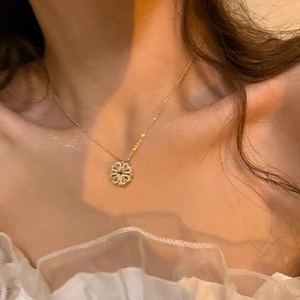 Close-up of a gold four-leaf clover pendant with pavé-set zircons on a delicate chain