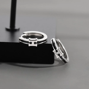Macro shot of silver hollow double-ring earrings featuring black H-shaped enamel inlay