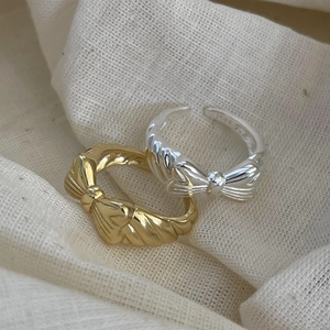 Macro shot of 925 sterling silver bow rings in gold and silver finish with adjustable bands