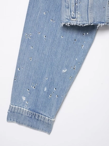 Détail d'une manche en jean bleu clair avec strass étincelants et ourlet effiloché