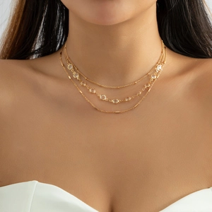 Detail of a three-layer gold necklace featuring crystal accents and layered chain design