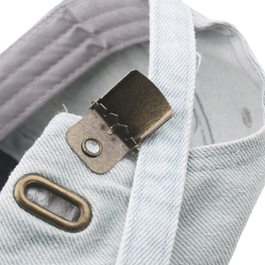 Close-up of adjustable bronze metal buckle and stitching on blue denim baseball cap