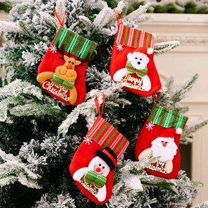 Detail of small Christmas stockings with reindeer and santa hanging on snowy tree