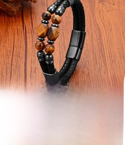 Detail view of double-layer black leather bracelet with tiger eye beads and steel clasp