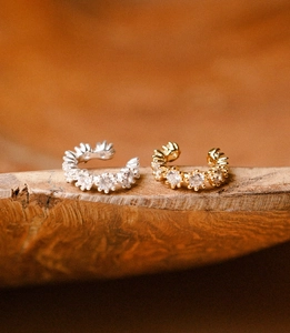 Detailed view of silver and gold ear cuffs set with sparkling white cubic zirconia